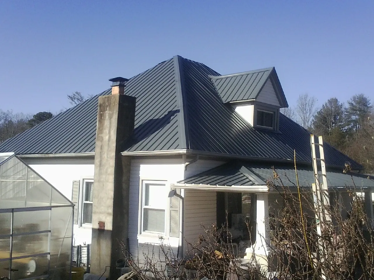Dark blue standing seam metal roof on a white farmhouse with dormer — Slate & Tile Roof Repair by Roofing Brothers in Blythewood
