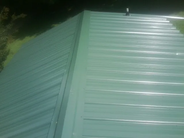 New green metal panels meeting at the ridge of a roof — Flat Roof Repair work by our crew in Blythewood
