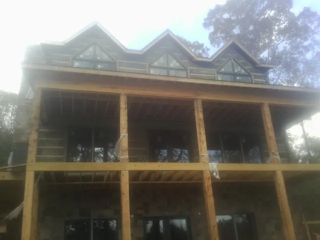Dormers and porch framing on a large log home under construction — Roof Coating work by our crew in Blythewood