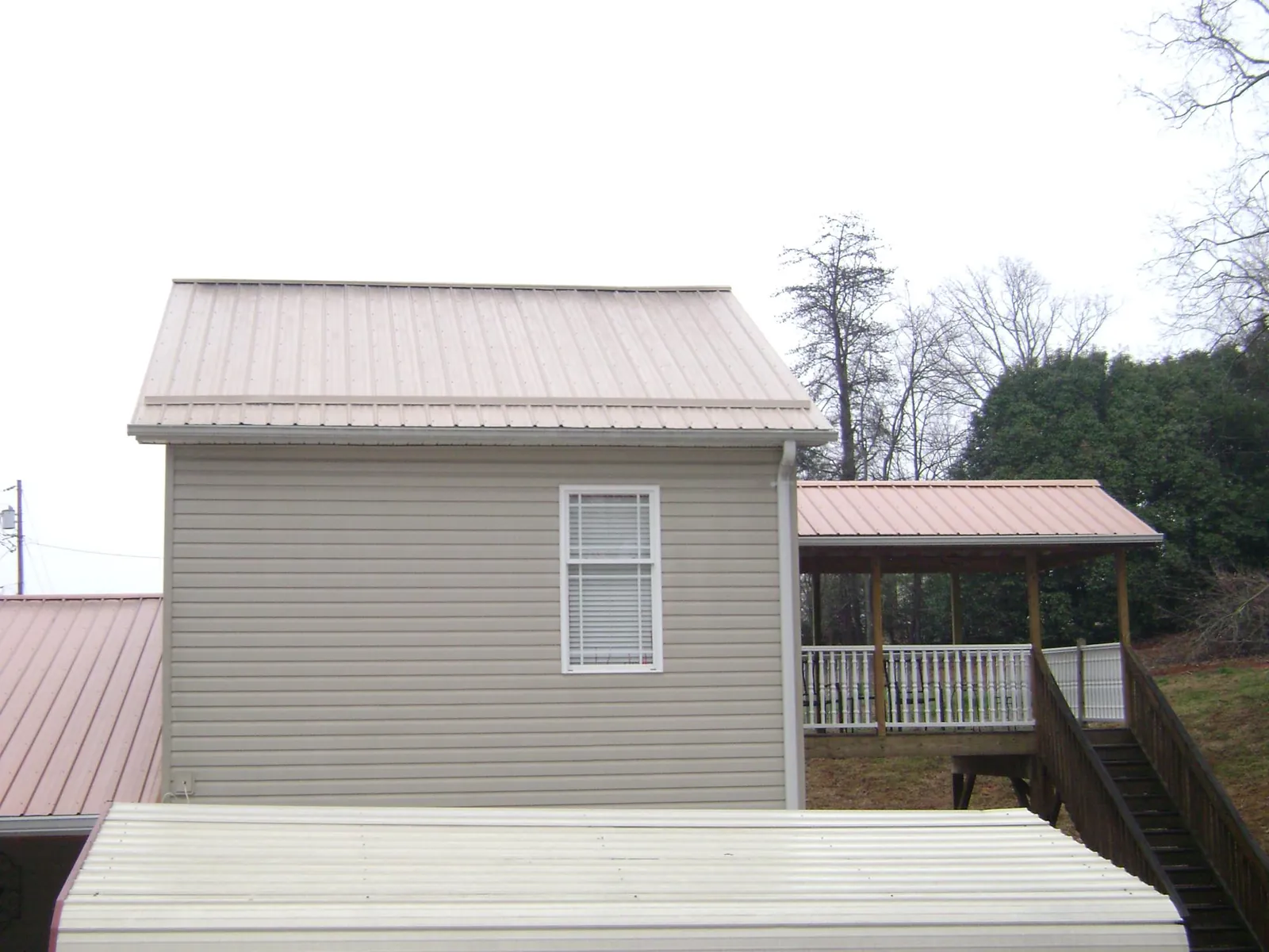 Tan metal roofs on a two story addition and attached porch, from a Roof Replacement job in Blythewood