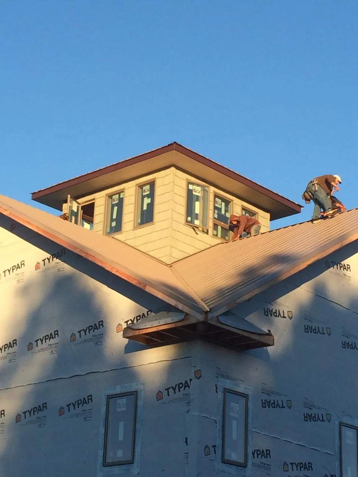 Roofers working around a rooftop cupola on a new metal roof at sunset — Roof Waterproofing in Blythewood by Roofing Brothers